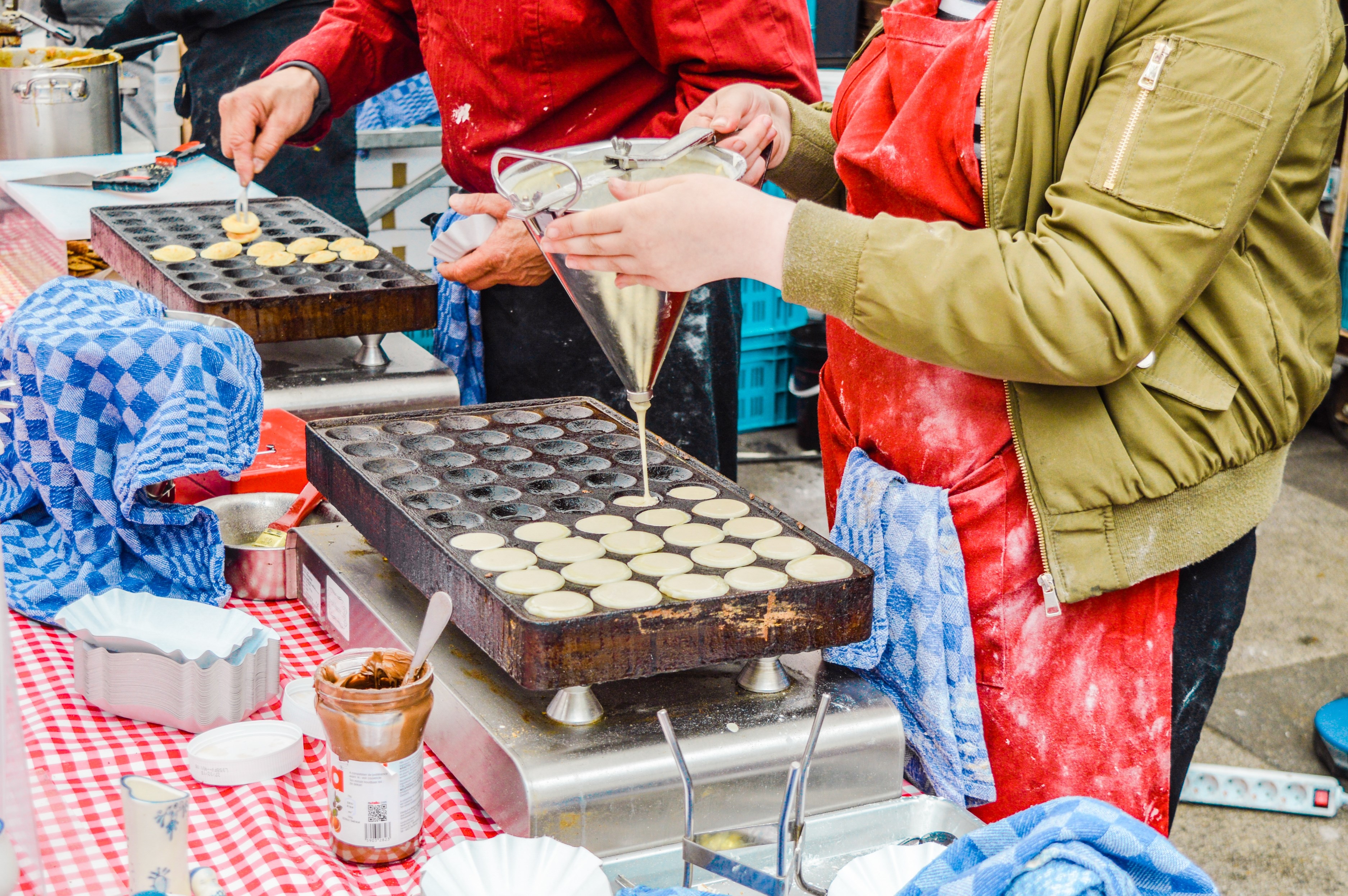 Two vendors prepare Traditional Dutch poffertjes at the Albert Cuyp market in Amsterdam